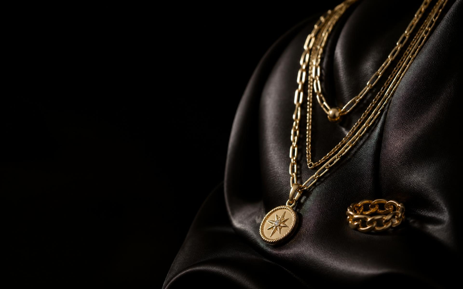 Layered yellow gold chains and a gold ring on black silk